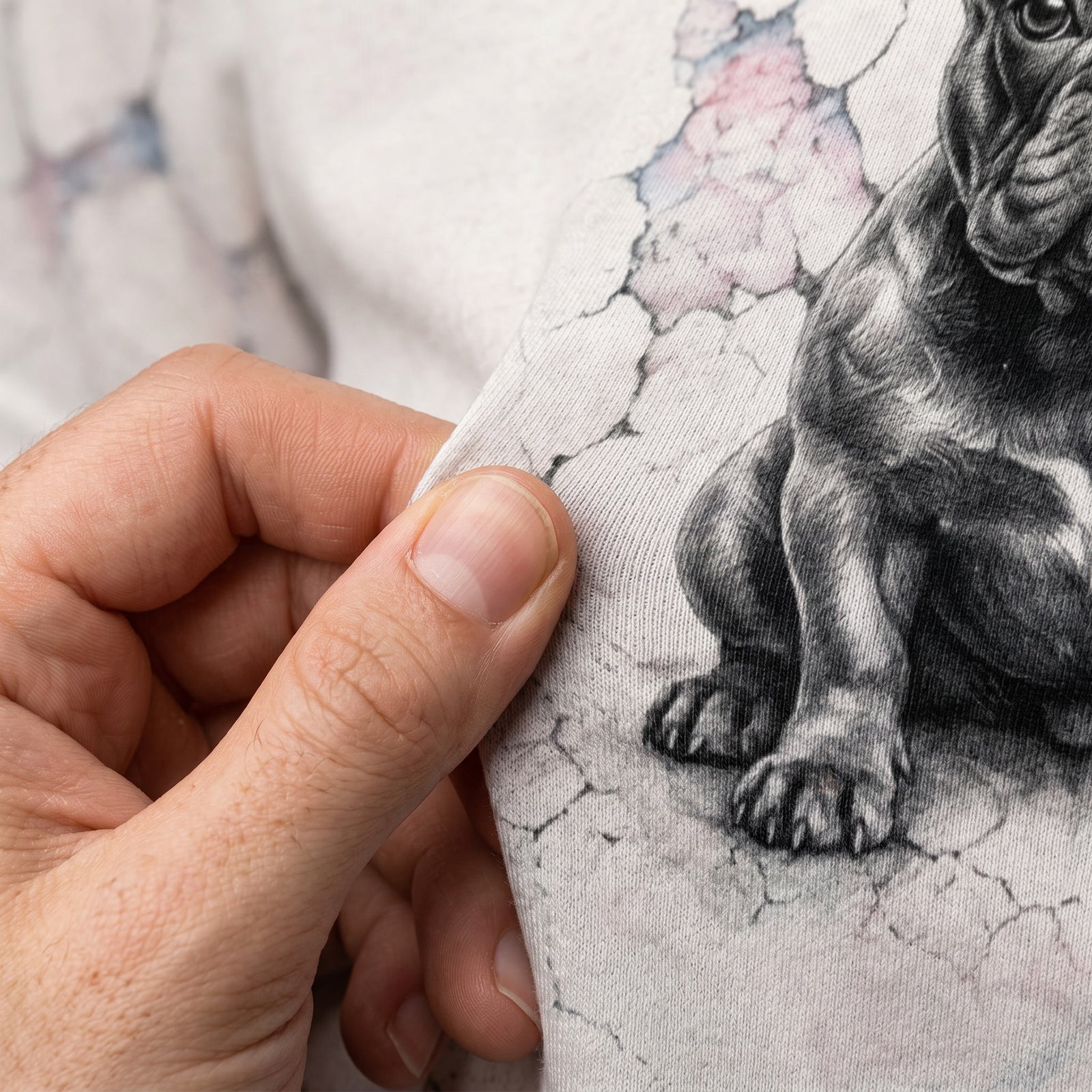 Hand holding a piece of fabric with a black and white dog illustration.