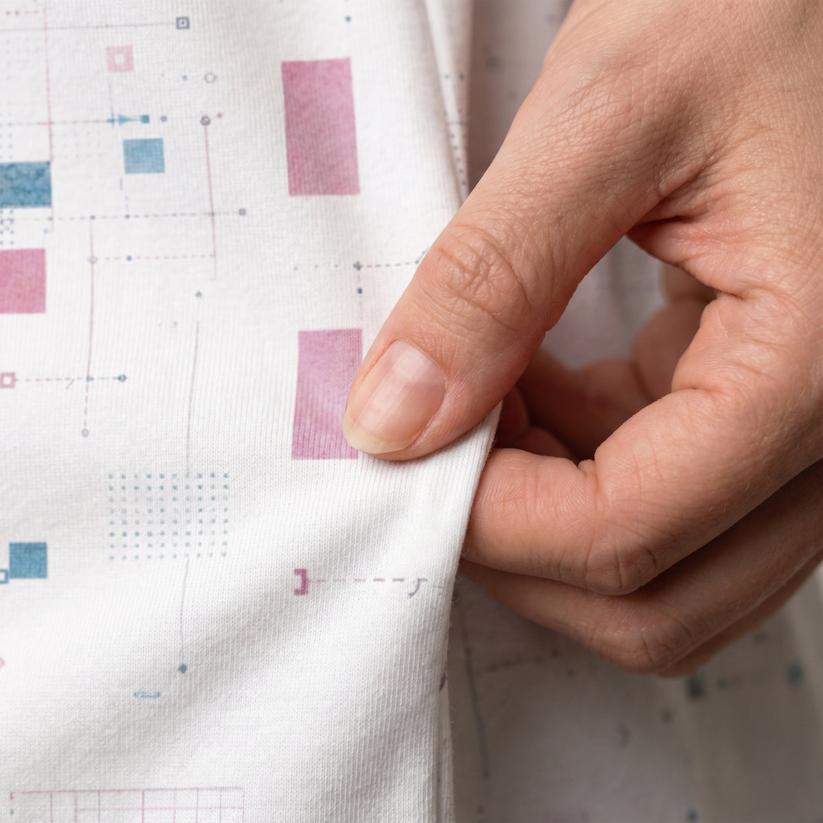 Hand holding a piece of fabric with colorful square patterns on a white background