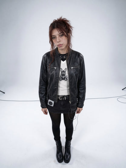 Person wearing a black leather jacket, graphic t-shirt, and black pants on a white background