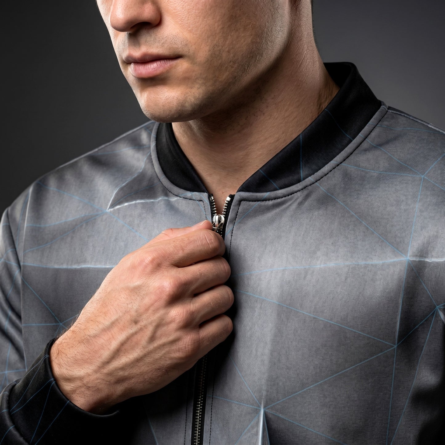 Man wearing a gray jacket with a geometric pattern on a dark background