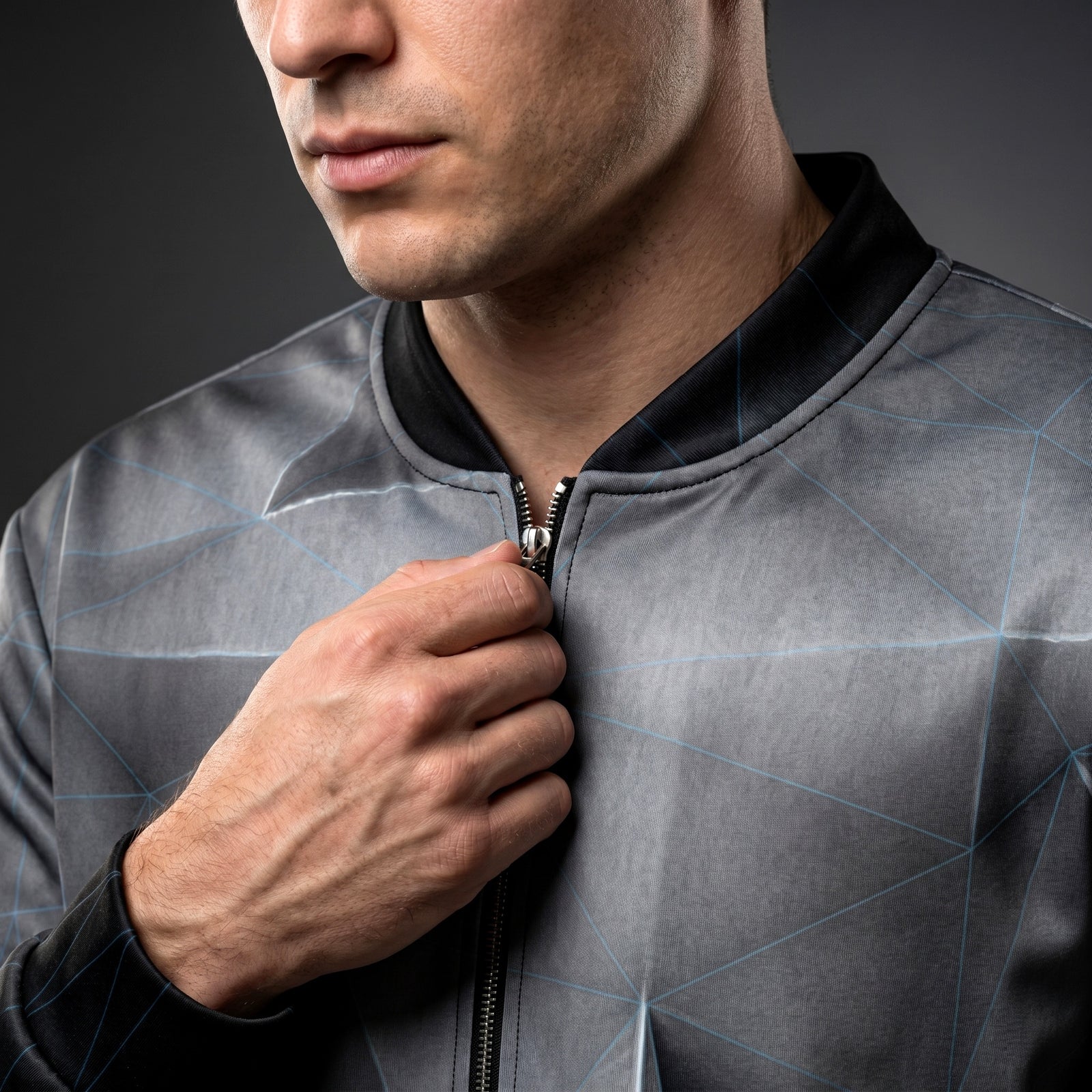 Man wearing a gray jacket with a geometric pattern on a dark background