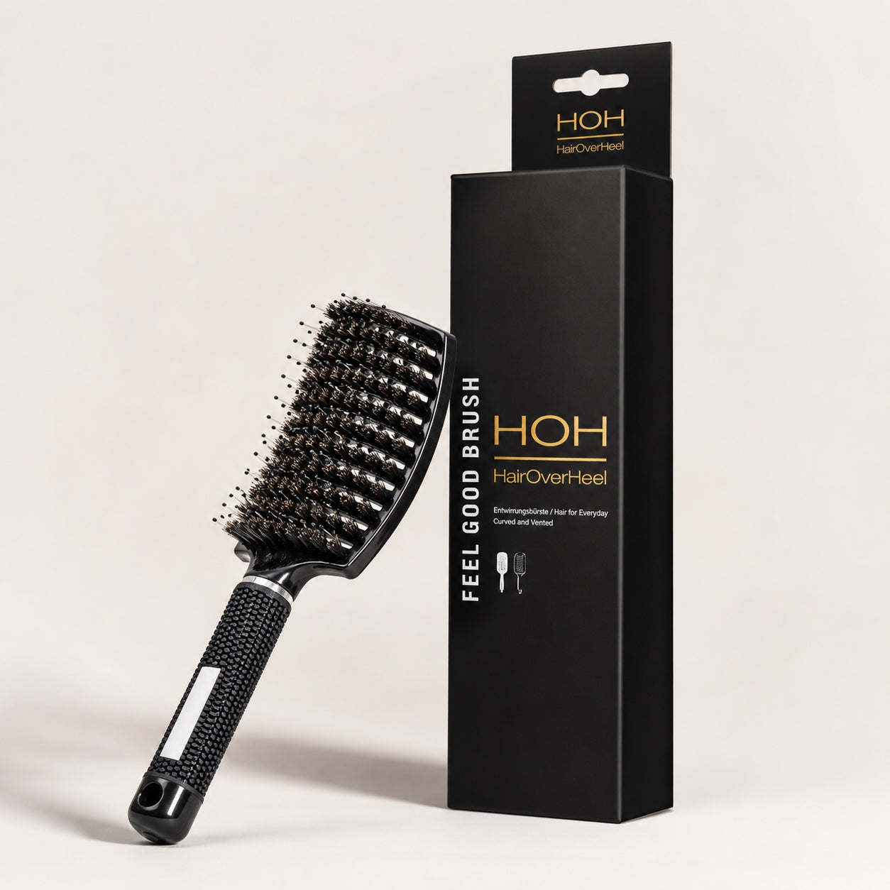 Black hairbrush with bristles and packaging on a beige background