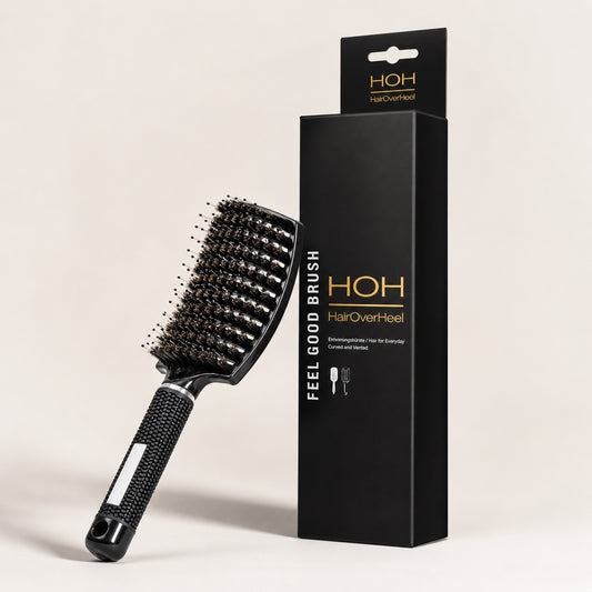 Black hairbrush with bristles and packaging on a beige background