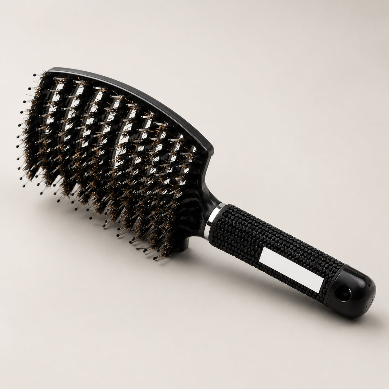 Black hairbrush with bristle head on a beige background
