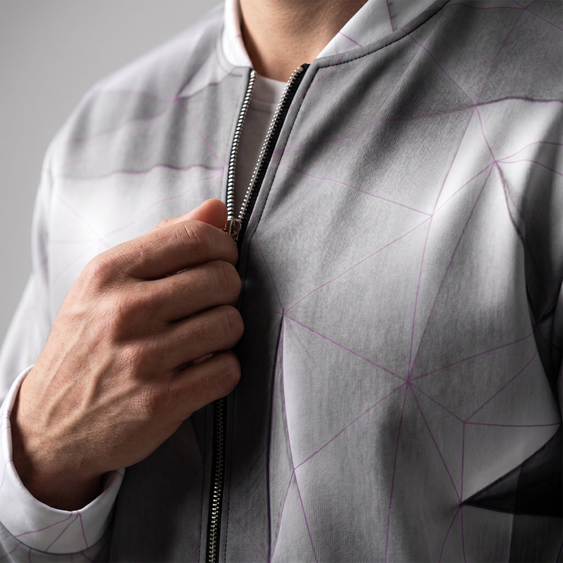 Person wearing a gray jacket with geometric pattern, focusing on the zipper area.