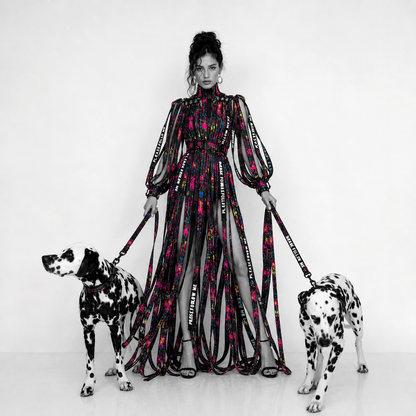 Woman in a colorful dress with two Dalmatian dogs on leashes against a white background