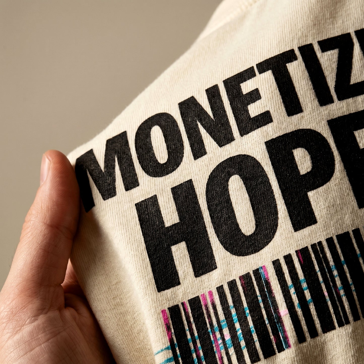 Beige tote bag with black text and colorful barcode held by a hand against a neutral background