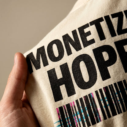 Beige tote bag with black text and colorful barcode held by a hand against a neutral background