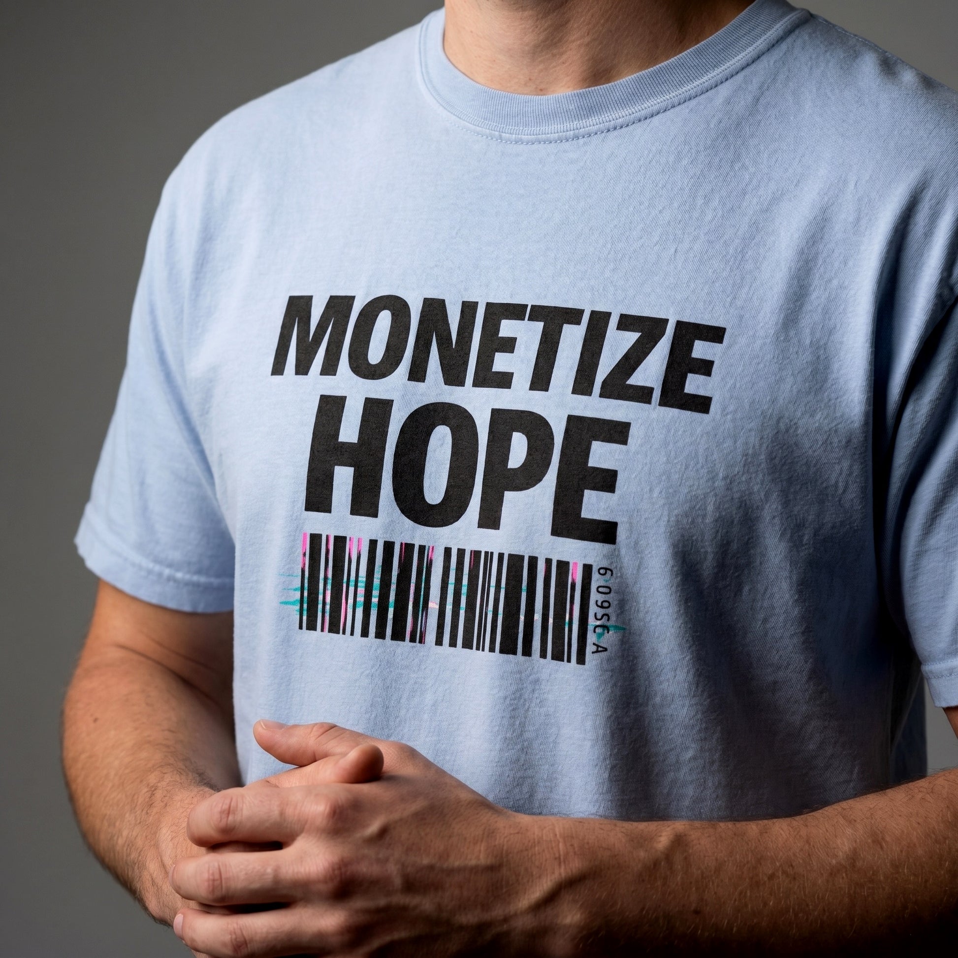 Light blue t-shirt with 'MONETIZE HOPE' text and barcode design on a gray background