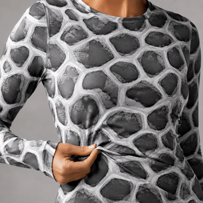 Close-up of the ANSO Cellular Mesh Midi Dress fabric being gently pulled by hand, showing the stretch jersey material, surface texture, and grey organic mesh pattern.
