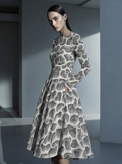 High-end editorial image of a model wearing the ANSO Cellular Mesh Midi Dress in a cool-toned architectural interior, highlighting the fitted waist, long sleeves, side pocket, and flared skirt.