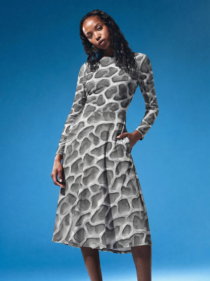 Fashion editorial image of a model wearing the ANSO Cellular Mesh Midi Dress against a vivid blue studio background, showing the long-sleeve fit, side pocket, and flared midi skirt.