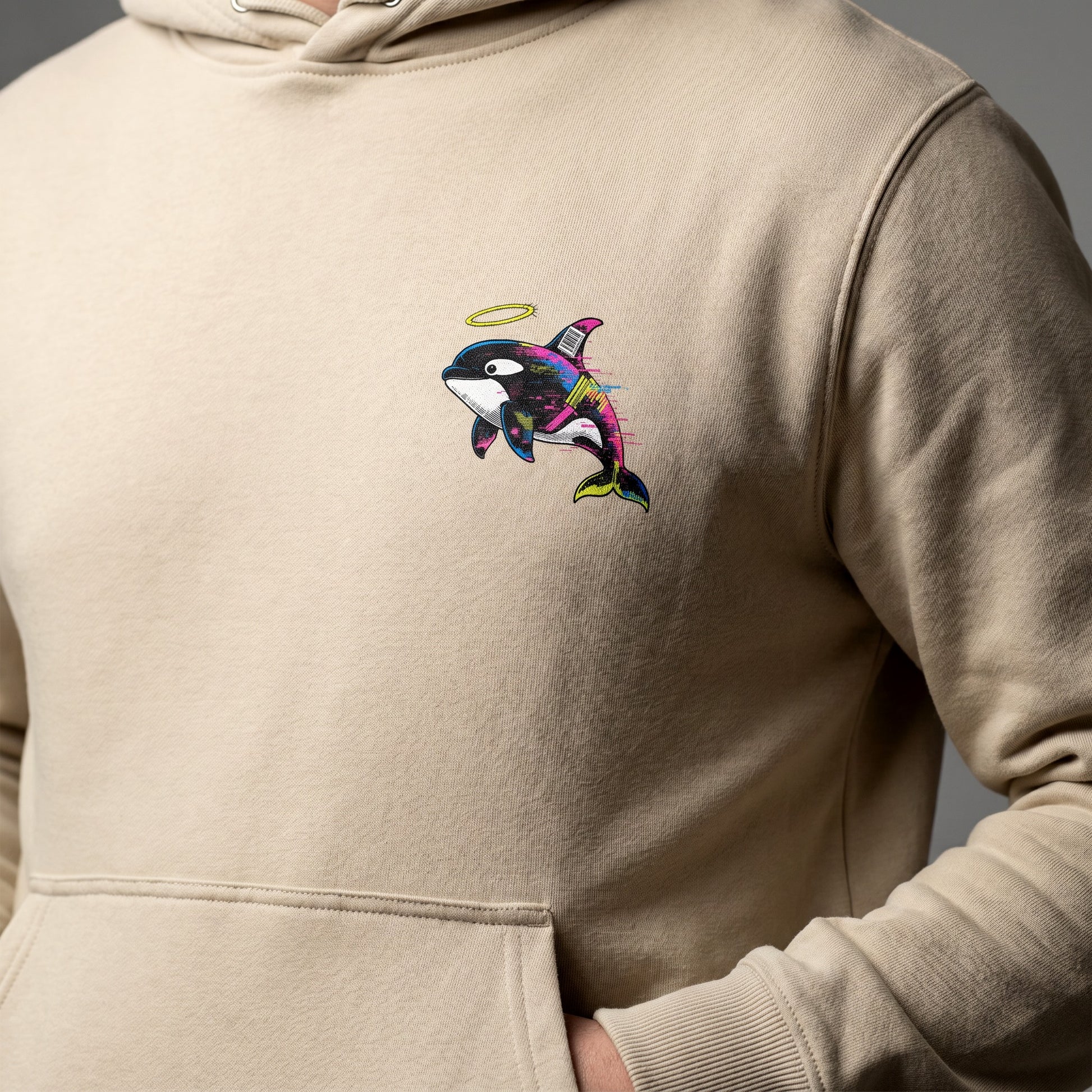 Beige hoodie with a colorful orca whale design on the chest against a gray background