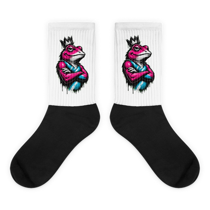 White and black cushioned crew socks with colorful crowned frog graphic near the upper leg, shown as a pair on a bright cyan background.