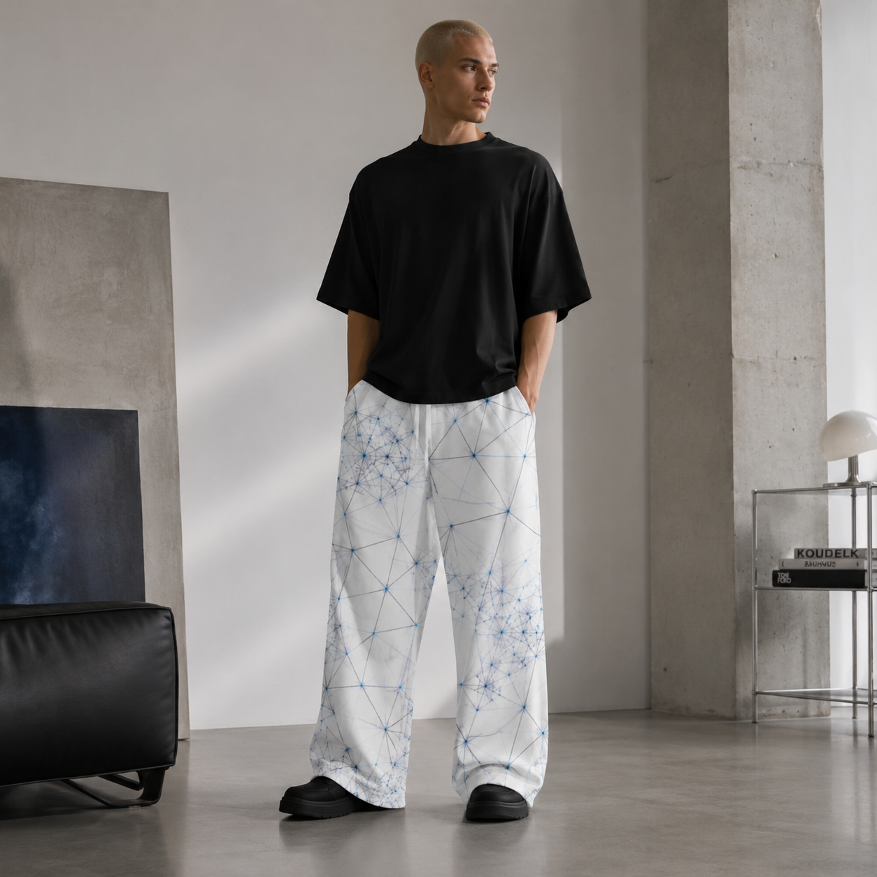 Person wearing a black t-shirt and white ANSO pants with geometric pattern in a modern room.