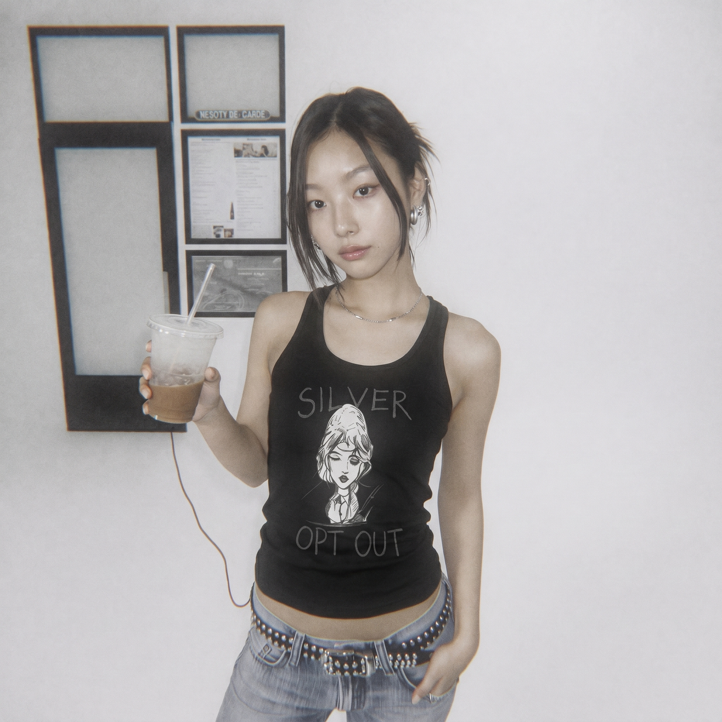 Woman wearing a black tank top with graphic design and text, holding a drink.