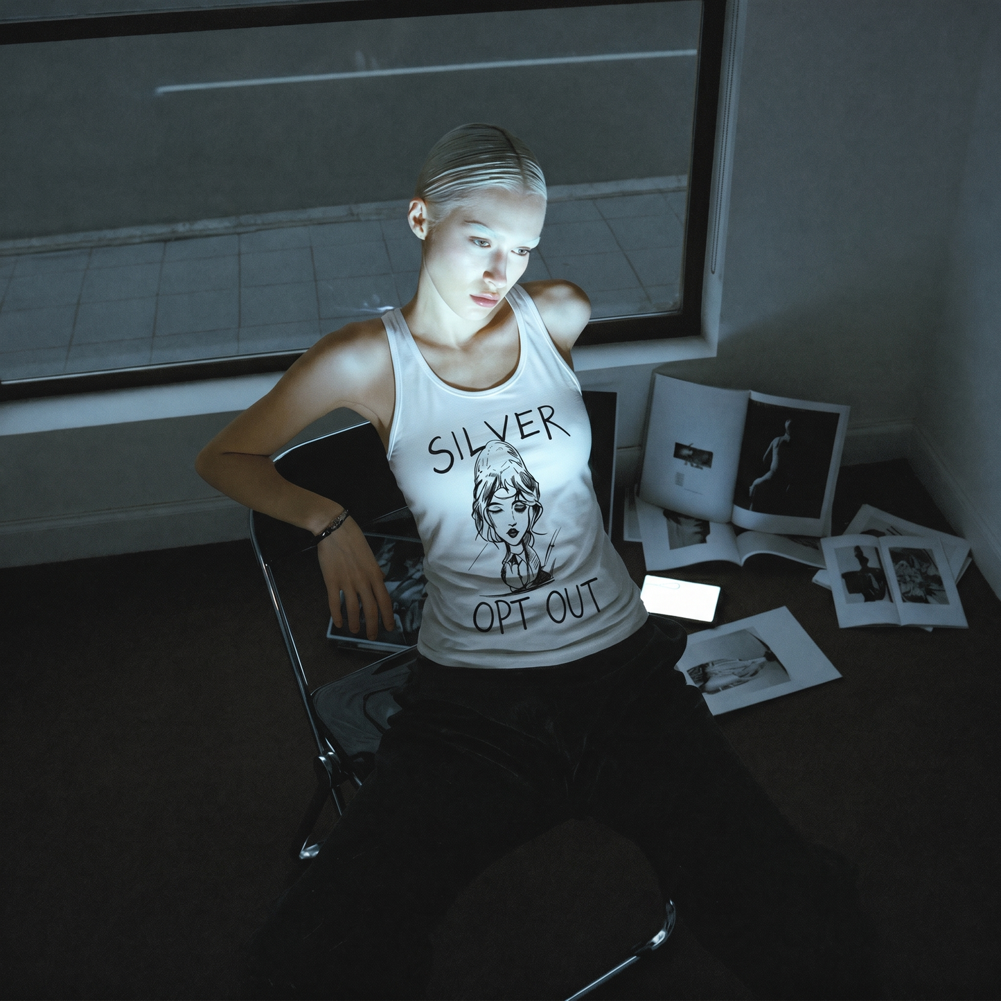 Person wearing a tank top with text sitting in a room with scattered photos.