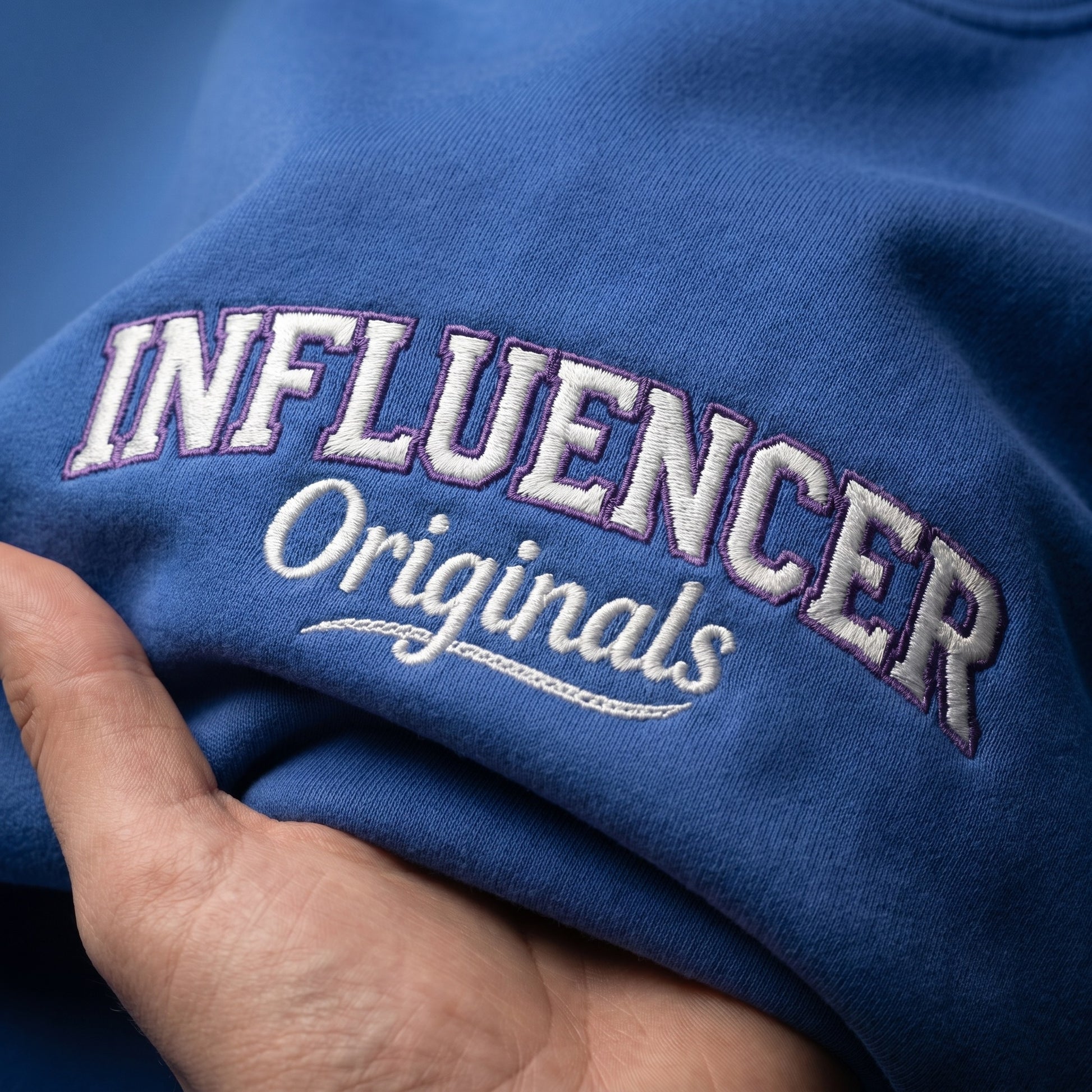 Blue fabric with 'INFLUENCER Originals' embroidered on it, held by a hand.