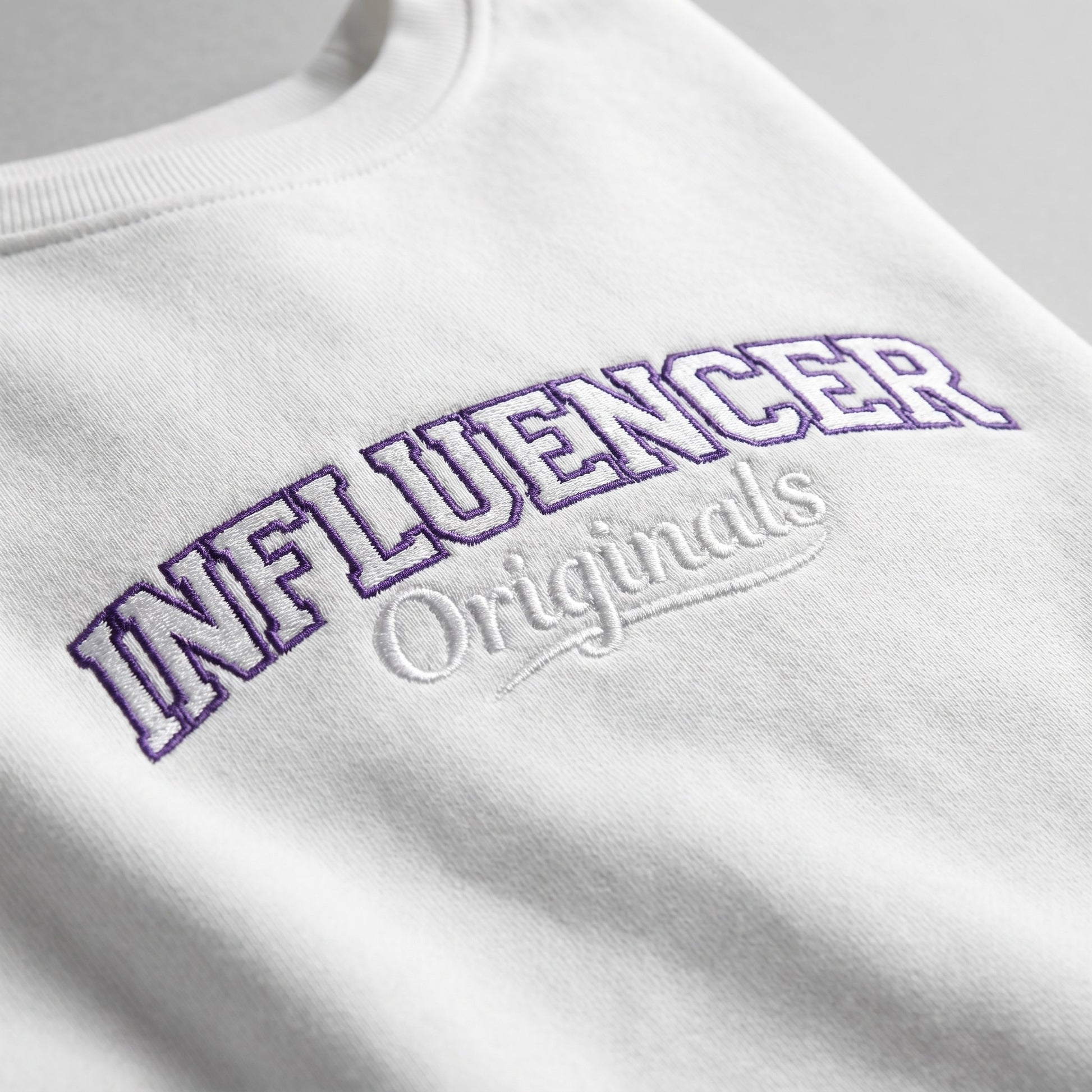 White sweatshirt with 'INFLUENCER Originals' text in purple on a light gray background