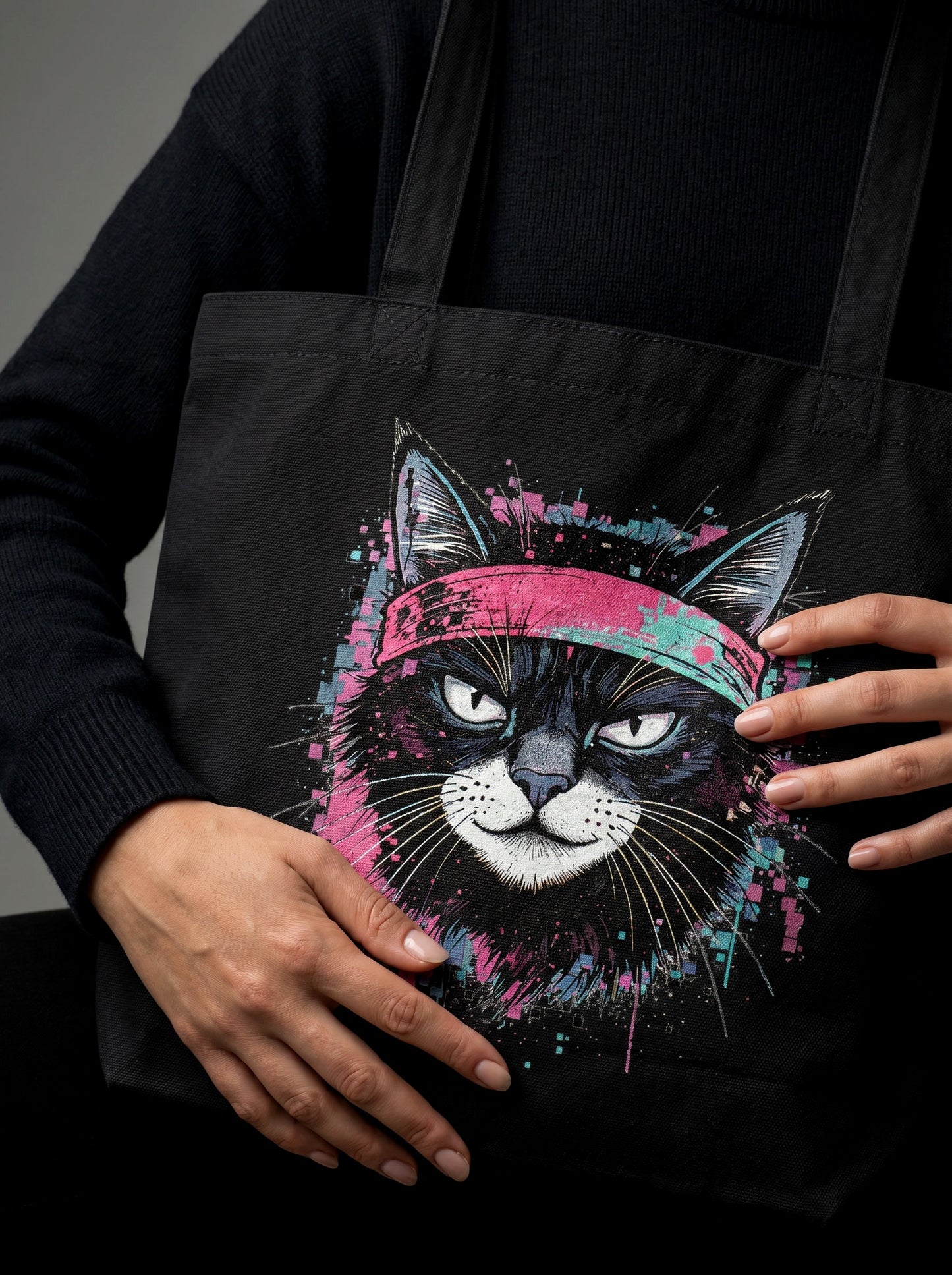 Black tote bag with a colorful cat design held by a person